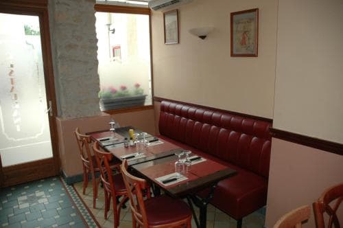 A cozy restaurant interior features red leather booths, wooden tables set for dining, and a tiled floor, creating an inviting atmosphere perfect for travelers seeking a quaint dining experience.