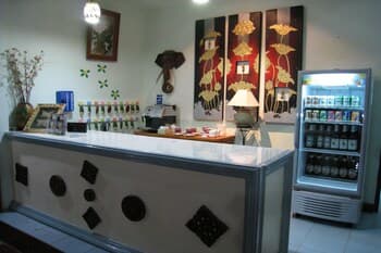 A cozy café interior features a stylish counter adorned with decorative elements, vibrant wall art, and a stocked beverage fridge, creating an inviting atmosphere perfect for travelers seeking a relaxing spot to unwind.