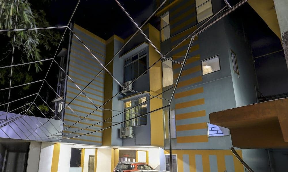 A vibrant, striped building illuminated at night with a protective wire mesh canopy creates an urban, secure atmosphere ideal for travelers seeking safety in city accommodations.