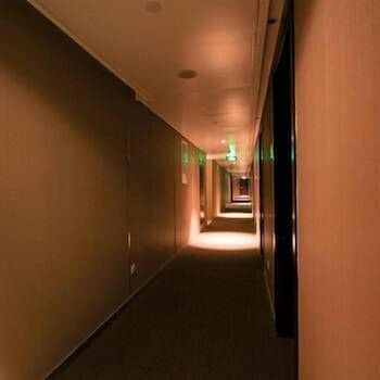 A warmly lit hotel corridor with carpeted floors and evenly spaced doors creates an inviting atmosphere, ideal for travelers seeking a comfortable stay.