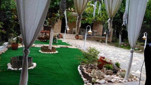 A serene garden pathway lined with draped curtains, potted plants, and stone lanterns creates an inviting atmosphere ideal for intimate outdoor events or romantic getaways.