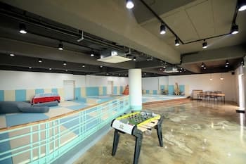 A spacious indoor recreational area features a polished floor, foosball tables, lounge seating, and a modern aesthetic, ideal for group activities or corporate retreats.