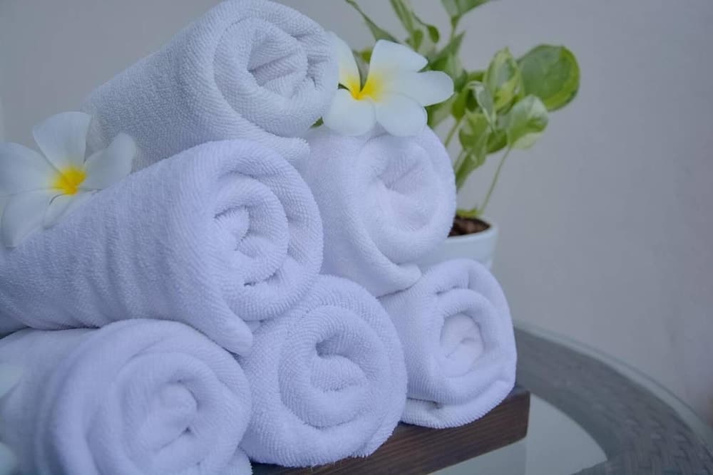 A serene spa setting features neatly rolled white towels adorned with fragrant frangipani flowers, creating a tranquil atmosphere ideal for relaxation and wellness retreats.