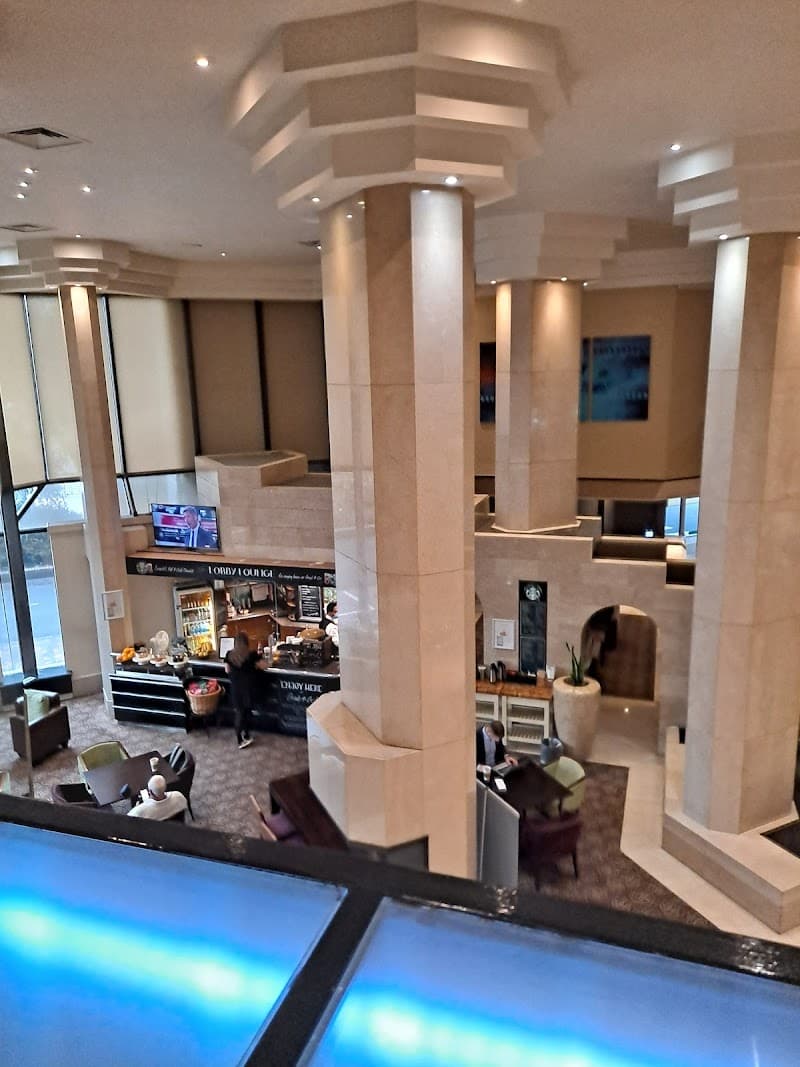 A modern hotel lobby in London features elegant tiered columns, cozy seating areas, and a vibrant lounge bar, creating a welcoming atmosphere ideal for travelers seeking comfort and style.