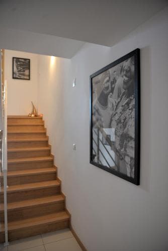 A cozy indoor staircase with wooden steps ascends beside a wall adorned with large black-and-white artwork, creating an inviting atmosphere ideal for a home tour or interior design inspiration.