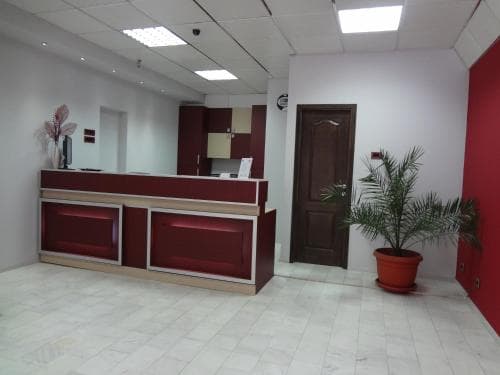 A modern reception area with a sleek red desk, white tiled floor, and potted plants creates a welcoming atmosphere ideal for business travelers seeking professional services.