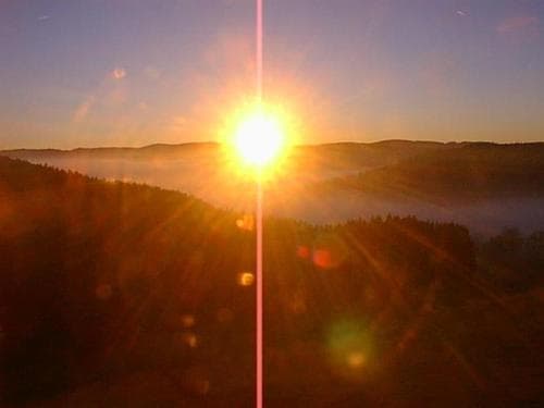 A serene sunrise over misty forested hills creates a tranquil atmosphere, ideal for nature photography and peaceful morning hikes.