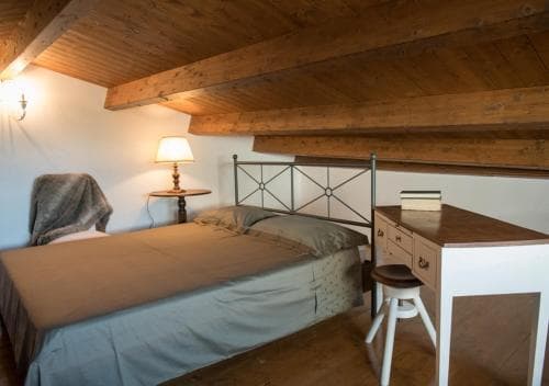 A cozy attic bedroom with wooden beams, warm lighting, and rustic furniture creates an inviting atmosphere perfect for travelers seeking a charming and intimate retreat.