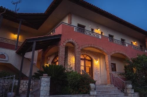 A warmly lit Mediterranean-style villa with arched doorways and balconies invites travelers to a cozy evening retreat, perfect for a romantic getaway or family vacation.