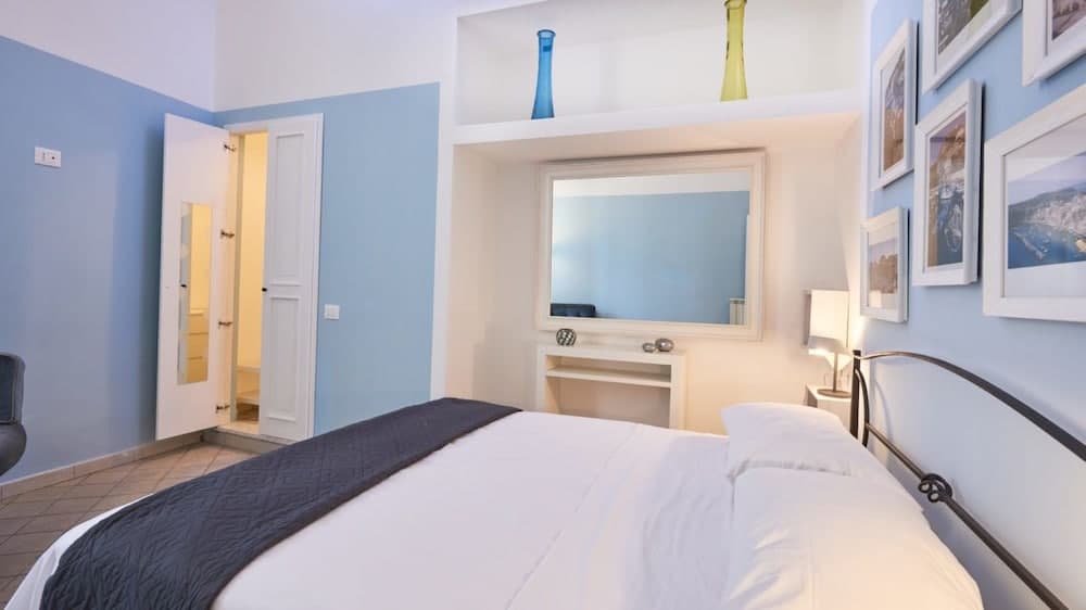 A cozy hotel room with light blue walls, framed artwork, and a neatly made bed invites travelers seeking comfort and relaxation in a serene setting.