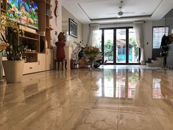A spacious living room with polished marble floors, vibrant decor, and large glass doors leading to an outdoor patio invites travelers seeking cozy yet elegant accommodations for relaxation.