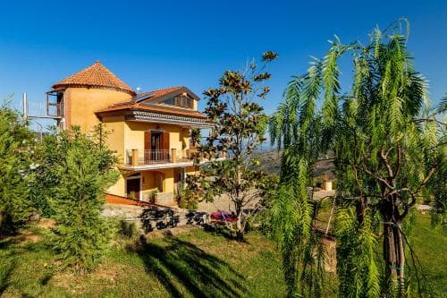 A serene countryside villa surrounded by lush greenery under a clear blue sky, ideal for tranquil retreats and nature lovers seeking a peaceful getaway.