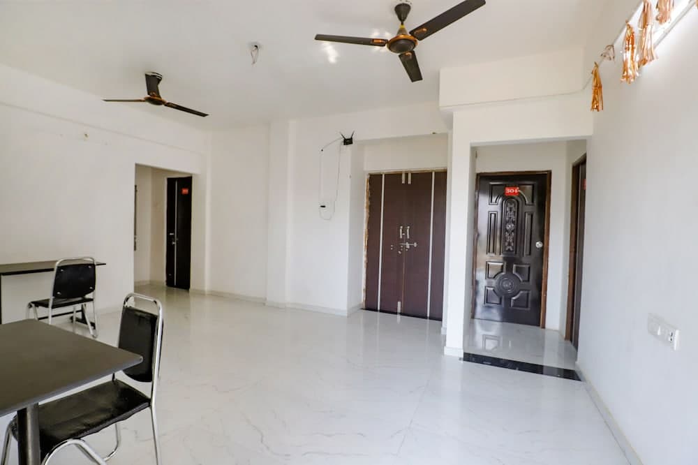 A bright, minimalist apartment interior features white marble flooring, ceiling fans, a simple dining setup, and festive decorations, ideal for travelers seeking a clean and spacious rental space.