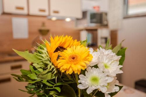 A vibrant bouquet of sunflowers and white chrysanthemums brightens a cozy kitchen setting, perfect for travelers seeking a homely and inviting atmosphere in their accommodations.