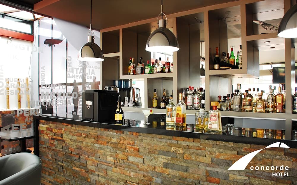 A cozy hotel bar with a stone facade, modern lighting, and an array of liquor bottles creates a welcoming atmosphere ideal for travelers seeking a relaxing drink spot.