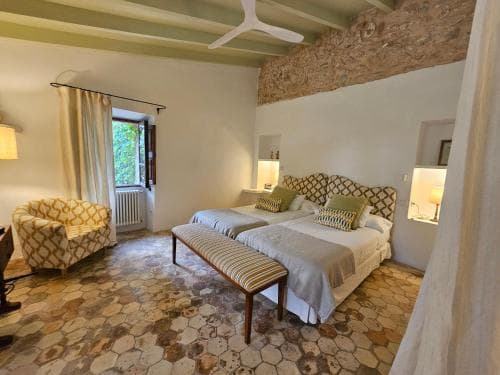 A cozy bedroom with rustic charm features patterned bedding, hexagonal tiled floors, and exposed brick walls, ideal for travelers seeking a serene and stylish retreat.