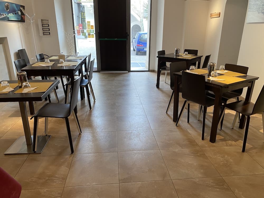 A cozy indoor café with neatly arranged tables and chairs, tiled floors, and large windows inviting natural light, creates a welcoming atmosphere ideal for travelers seeking a quiet spot to relax or work.