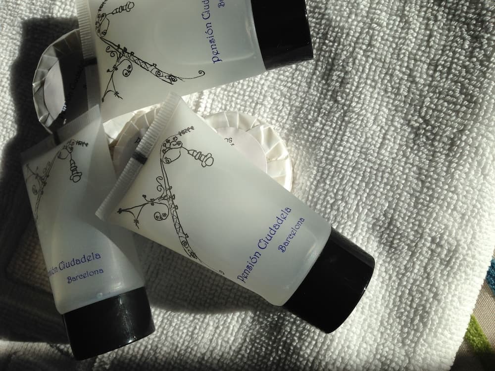 Luxurious toiletries from Pension Ciudadela Barcelona rest on a plush white towel, evoking a serene spa-like atmosphere ideal for travelers seeking comfort and elegance.