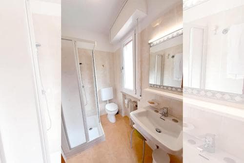 A cozy, well-lit bathroom with a shower, toilet, sink, and large mirror creates a serene atmosphere ideal for travelers seeking comfort in accommodations.