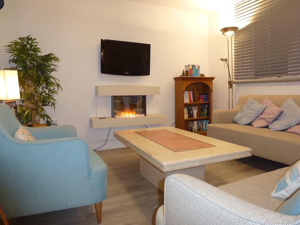 A cozy living room with modern furnishings, a warm fireplace, and soft lighting creates an inviting atmosphere ideal for relaxation or a family vacation rental.