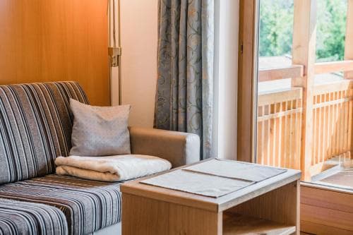 A cozy hotel room with a striped sofa, neatly folded towels, and a wooden coffee table by a balcony door, evoking a serene and inviting atmosphere ideal for travelers seeking relaxation.