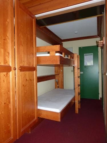 A cozy hostel room featuring wooden bunk beds, a green door, and warm lighting, ideal for budget travelers seeking a comfortable and communal stay.