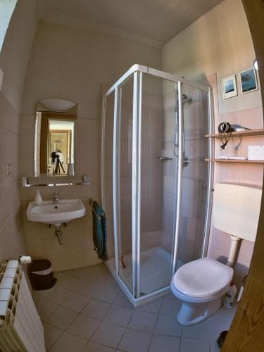 A cozy hotel bathroom features a compact shower stall, sink, toilet, and mirror, ideal for travelers seeking efficient space in a functional setting.