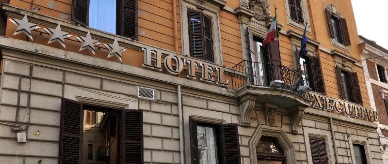 A charming European hotel facade adorned with five stars and flags, exuding a welcoming atmosphere ideal for travelers seeking a cozy urban retreat.