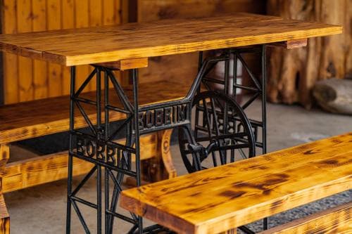 A rustic wooden table with industrial-style metal legs stands invitingly in a cozy cabin interior, perfect for travelers seeking a charming and unique dining spot.