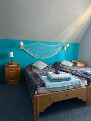 A cozy attic bedroom with wooden beds adorned in blue linens, a decorative net on the wall, and soft lighting creates a serene retreat ideal for travelers seeking a peaceful stay.