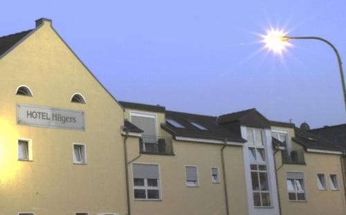 A cozy evening view of a quaint hotel with arched windows and a glowing streetlamp, ideal for travelers seeking a charming urban retreat.
