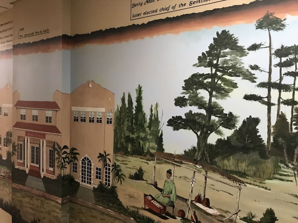 A serene mural depicts the Seminole Inn surrounded by lush greenery and palm trees, capturing a tranquil historical scene ideal for cultural tourism exploration.