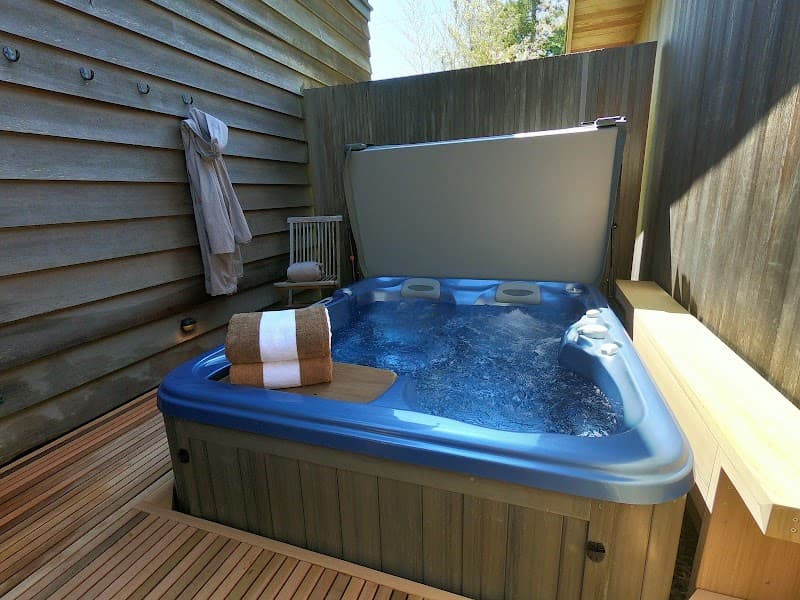 A serene outdoor hot tub on a wooden deck surrounded by privacy walls, perfect for relaxing getaways in coastal cabins.