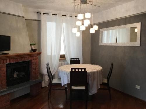 A cozy dining area with a round table, chairs, and a brick fireplace creates an inviting atmosphere in a modern apartment, perfect for travelers seeking a warm and comfortable stay.