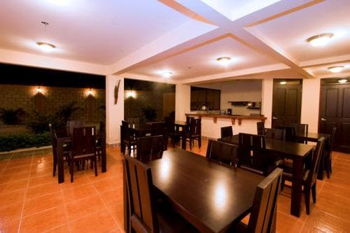 A warmly lit indoor dining area with polished wooden tables and chairs set against terracotta tiles, ideal for group gatherings or intimate dinners in a cozy restaurant setting.