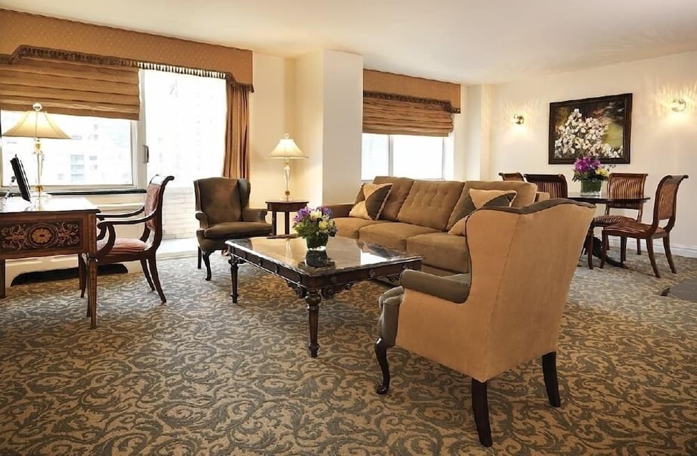 A cozy hotel lounge features plush seating, floral arrangements, and warm lighting, creating an inviting atmosphere ideal for travelers seeking relaxation or business meetings.