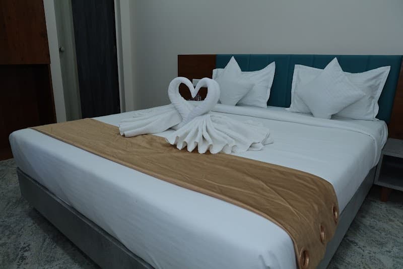A cozy hotel room in Dwarka, Gujarat, features a neatly made bed adorned with artistic towel swans forming a heart, inviting travelers seeking comfort and charm.