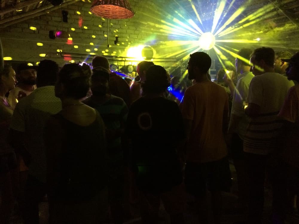 A lively indoor dance party scene with vibrant laser lights and a brick ceiling, capturing the energetic mood of a social gathering, ideal for nightlife enthusiasts seeking entertainment options.
