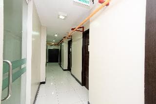 A well-lit hotel corridor with white walls, glass doors, and orange pipes creates a clean and functional atmosphere, ideal for travelers seeking accommodation details online.