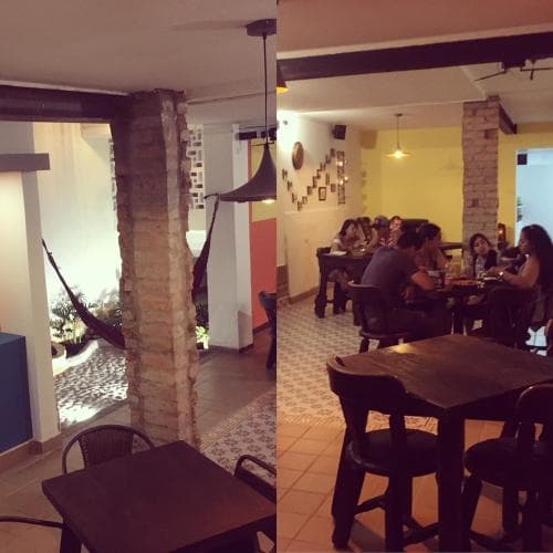 A cozy indoor café with rustic brick columns, wooden tables, and patrons enjoying meals creates an inviting atmosphere perfect for travelers seeking a relaxed dining experience.