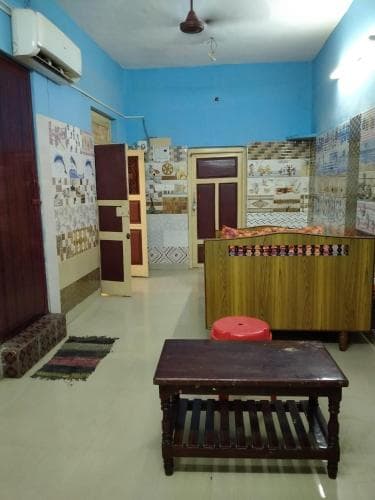 A cozy indoor space with vibrant blue walls, patterned tiles, and wooden furniture exudes a homely atmosphere, ideal for travelers seeking a unique cultural stay experience.