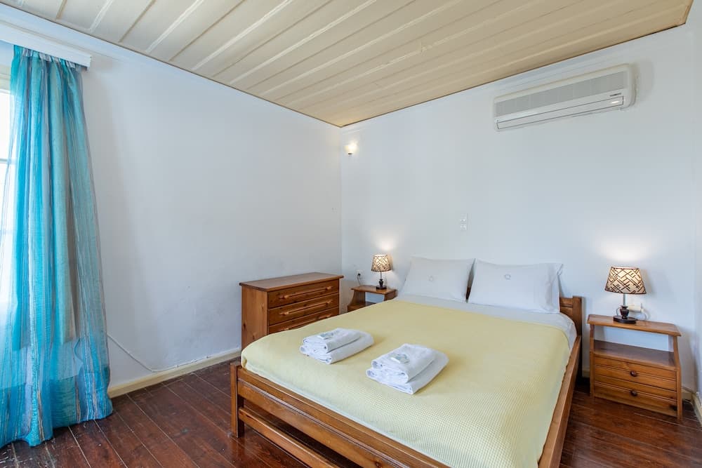 A cozy bedroom with wooden furniture, blue curtains, and soft lighting creates a serene atmosphere ideal for travelers seeking relaxation in a vacation rental.