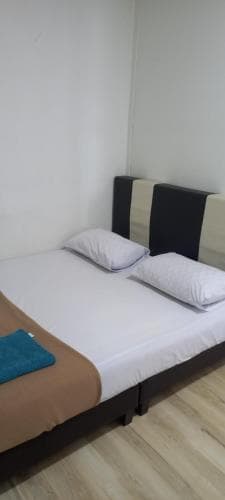A cozy bedroom with a neatly made bed featuring white pillows, a brown blanket, and a blue towel on wooden flooring, ideal for budget travelers seeking simple accommodations.