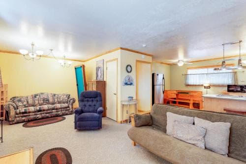 A cozy living room with warm yellow walls, comfortable sofas, and a kitchenette in the background offers a welcoming atmosphere for travelers seeking a homey retreat.