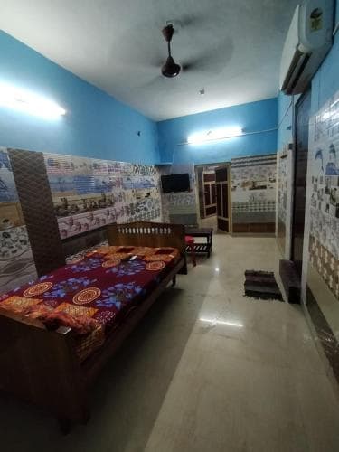 A cozy bedroom with blue walls, patterned bedding, and wall art creates a welcoming atmosphere, ideal for travelers seeking a comfortable and budget-friendly accommodation option.