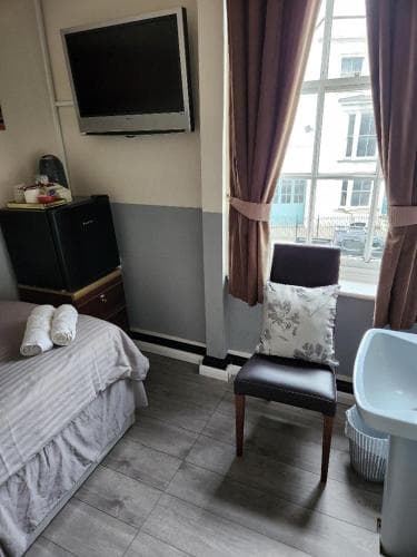 A cozy hotel room with a neatly made bed, flat-screen TV, and a chair by the window overlooking a scenic view, ideal for travelers seeking comfort and relaxation.