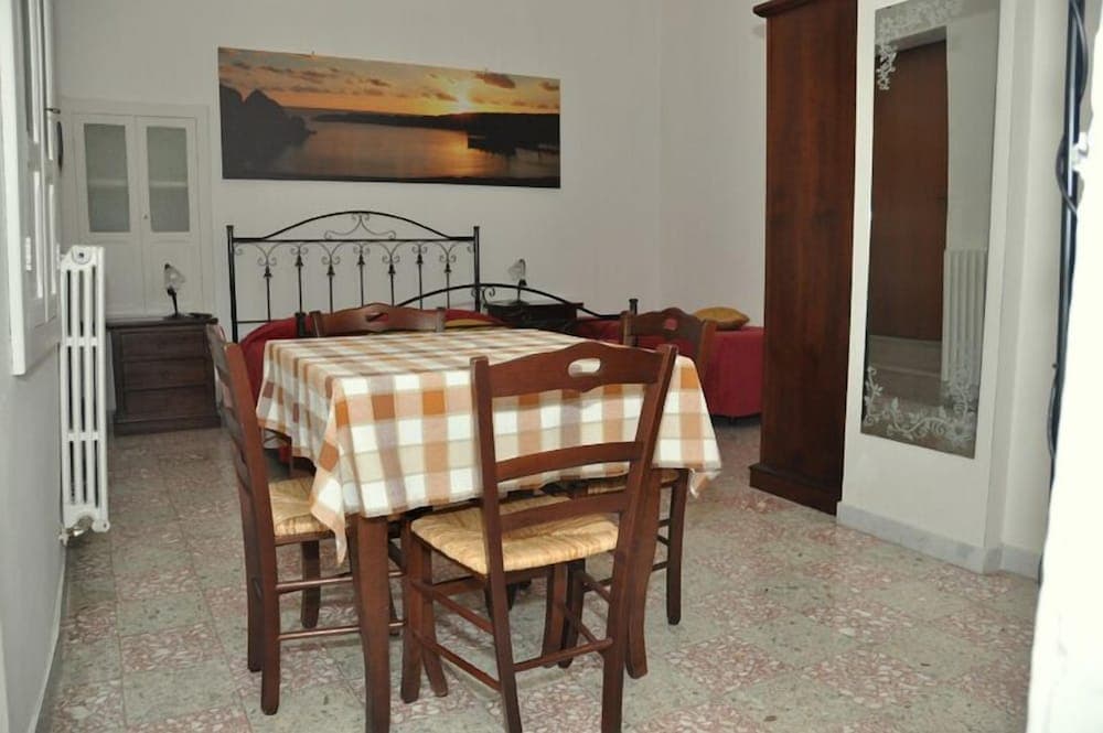 A cozy dining area with a checkered tablecloth, wooden chairs, and a serene sunset painting creates an inviting atmosphere in a quaint vacation rental.