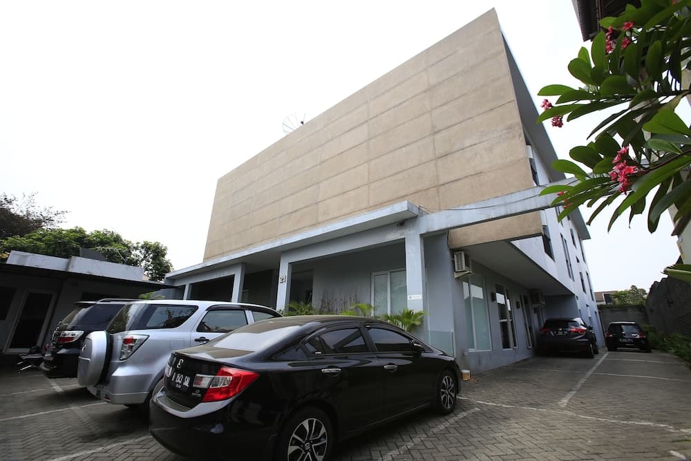 A modern building with parked cars and lush greenery creates a serene urban setting ideal for business travelers seeking a quiet accommodation spot.