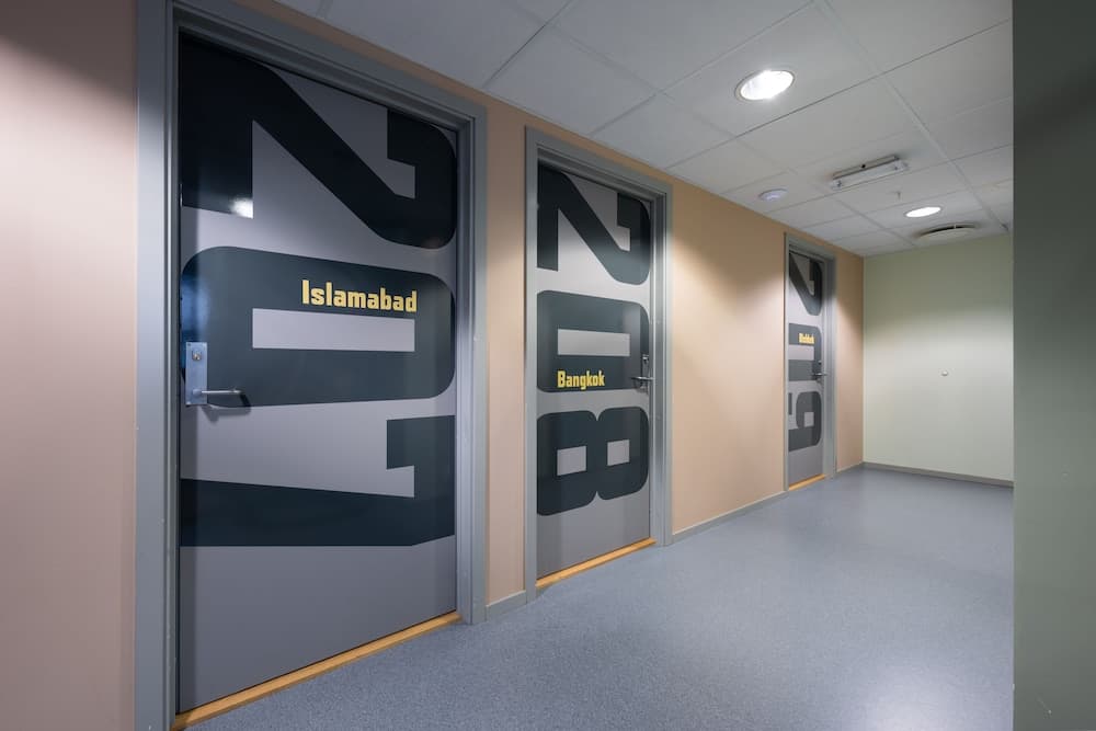 A modern hallway lined with doors labeled "Islamabad" and "Bangkok," creating an international ambiance ideal for business travelers exploring themed conference rooms or offices.