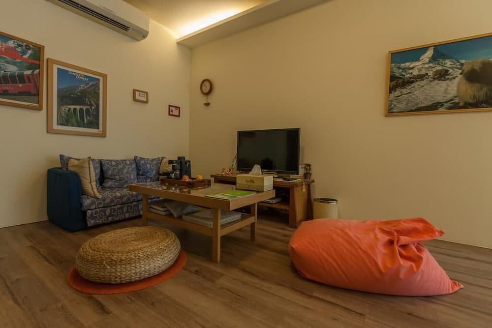A cozy living room with wooden flooring, vibrant bean bags, framed mountain art, and a warm ambiance is ideal for travelers seeking a comfortable and inviting accommodation space.